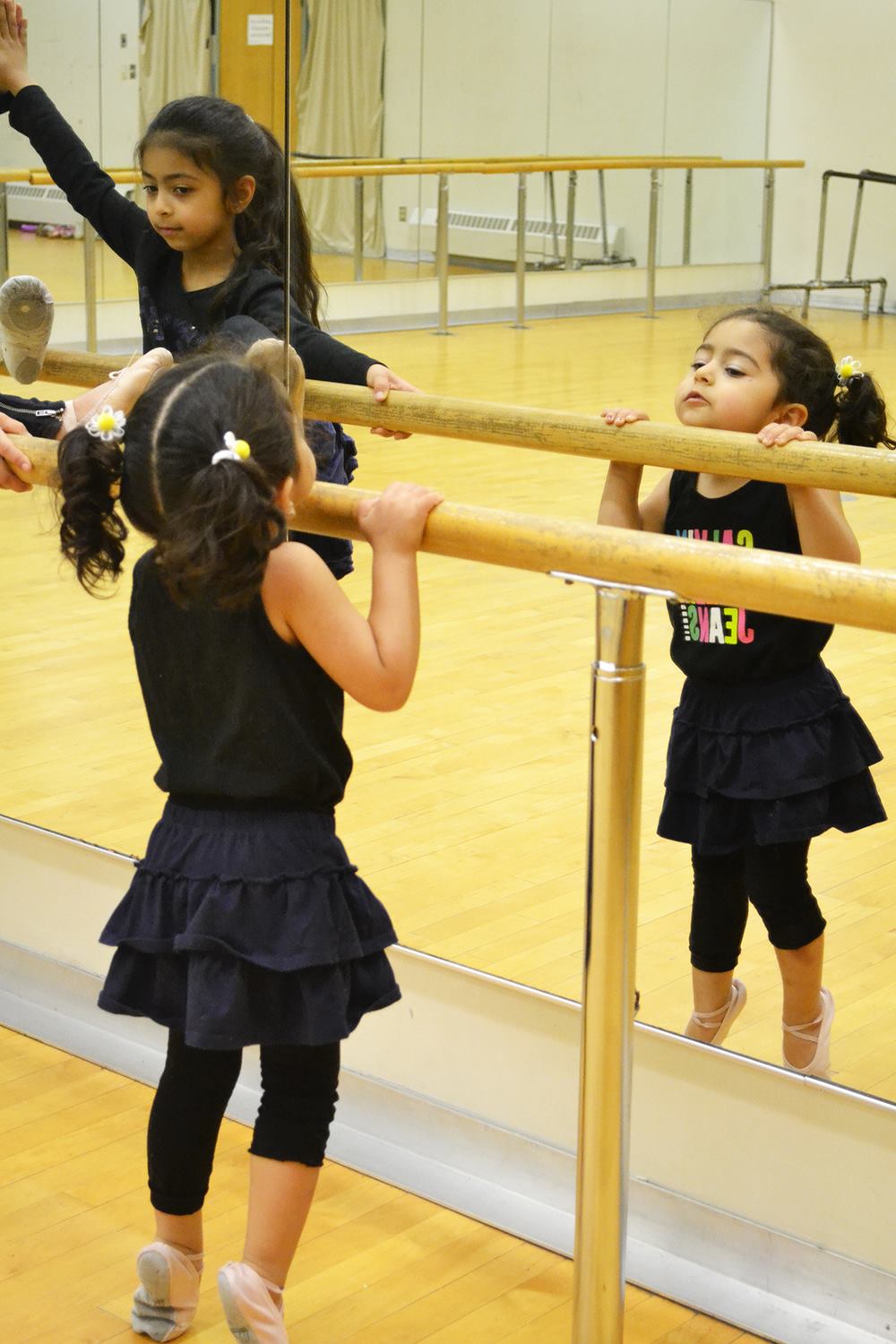 Young children practising at a dance studio barre